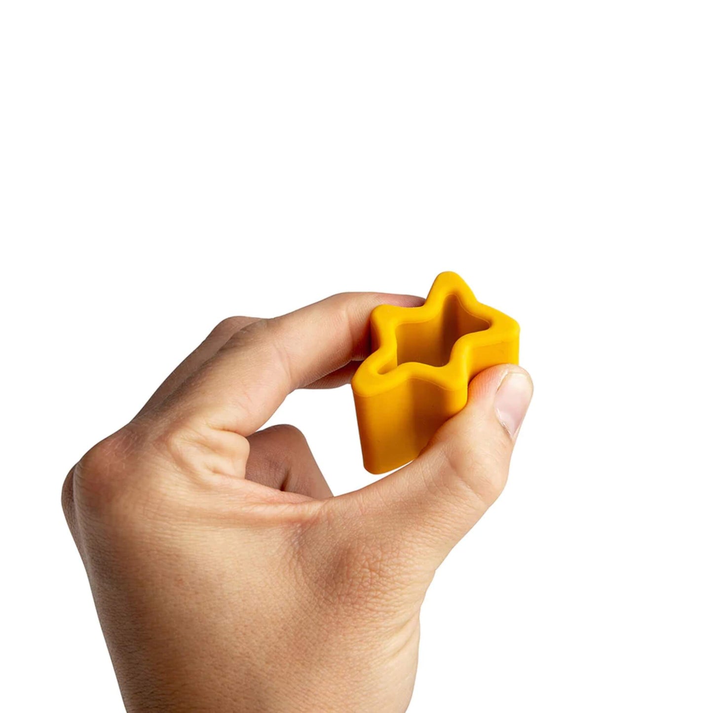 A close-up of a hand holding a yellow silicone nought piece, showing the star-shaped interior and gentle curve for easy gripping.