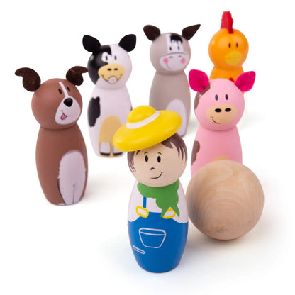 Wooden farm-themed skittles including a farmer, pig, dog, chicken, cow, and donkey arranged in two rows, with a wooden ball in the foreground.