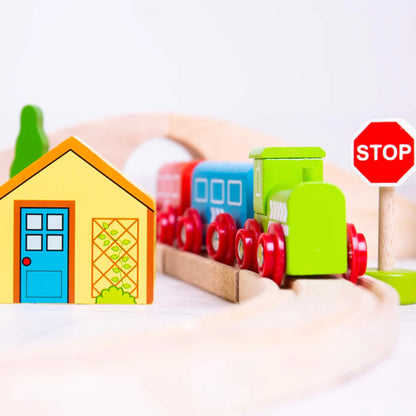 Train passing a yellow wooden house and red stop sign on the track.