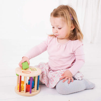 Young child playing with the Bigjigs Toys Rolling Shape Sorter, carefully fitting a green square piece into the matching slot.