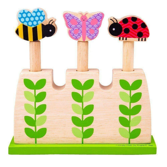 Wooden pop-up toy from Bigjigs Toys with three colourful bugs—a bumblebee, butterfly, and ladybird—set in a green leaf-themed garden base.