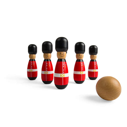 A line-up of six Bigjigs Toys Guardsman Skittles standing upright, with a natural wooden ball in the foreground ready to roll.