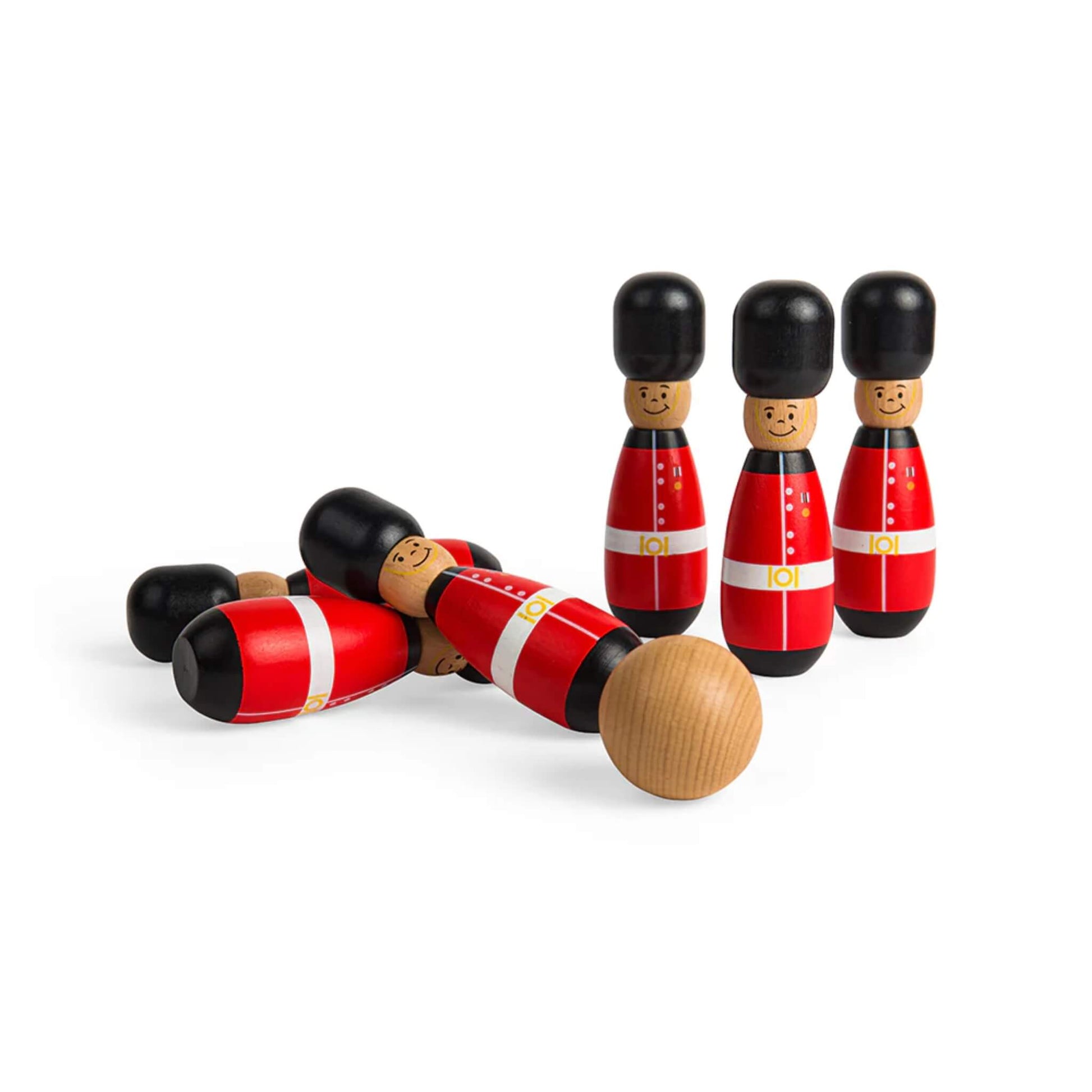 Several wooden guardsman skittles knocked over mid-play, while three remain standing in the background with a wooden ball in motion.