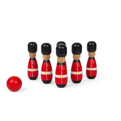 Six guardsman skittles neatly arranged in two rows, facing forward, with a bright red ball placed off to the side.