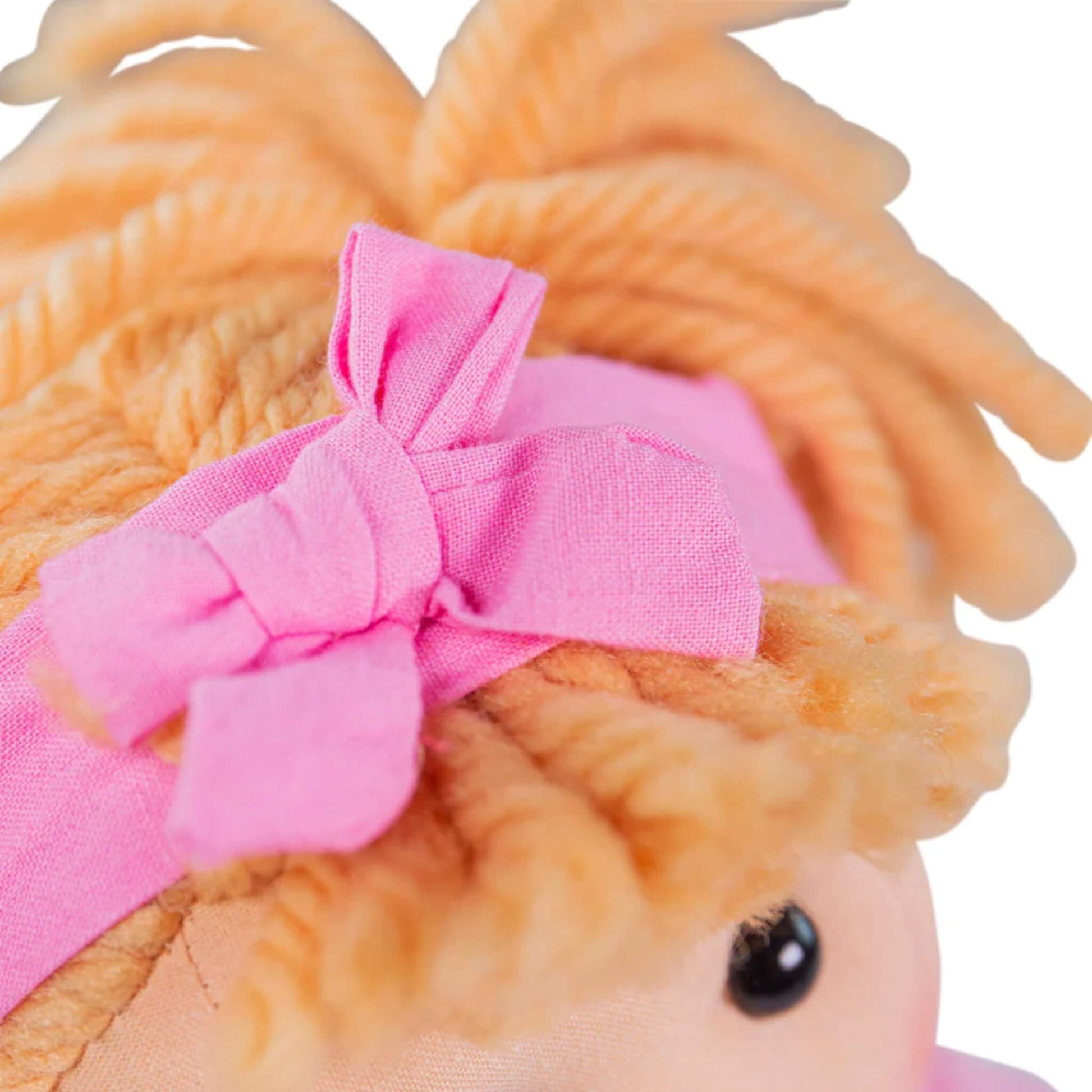 Close-up of pink fabric bow tied around her hairband, highlighting stitching and material.