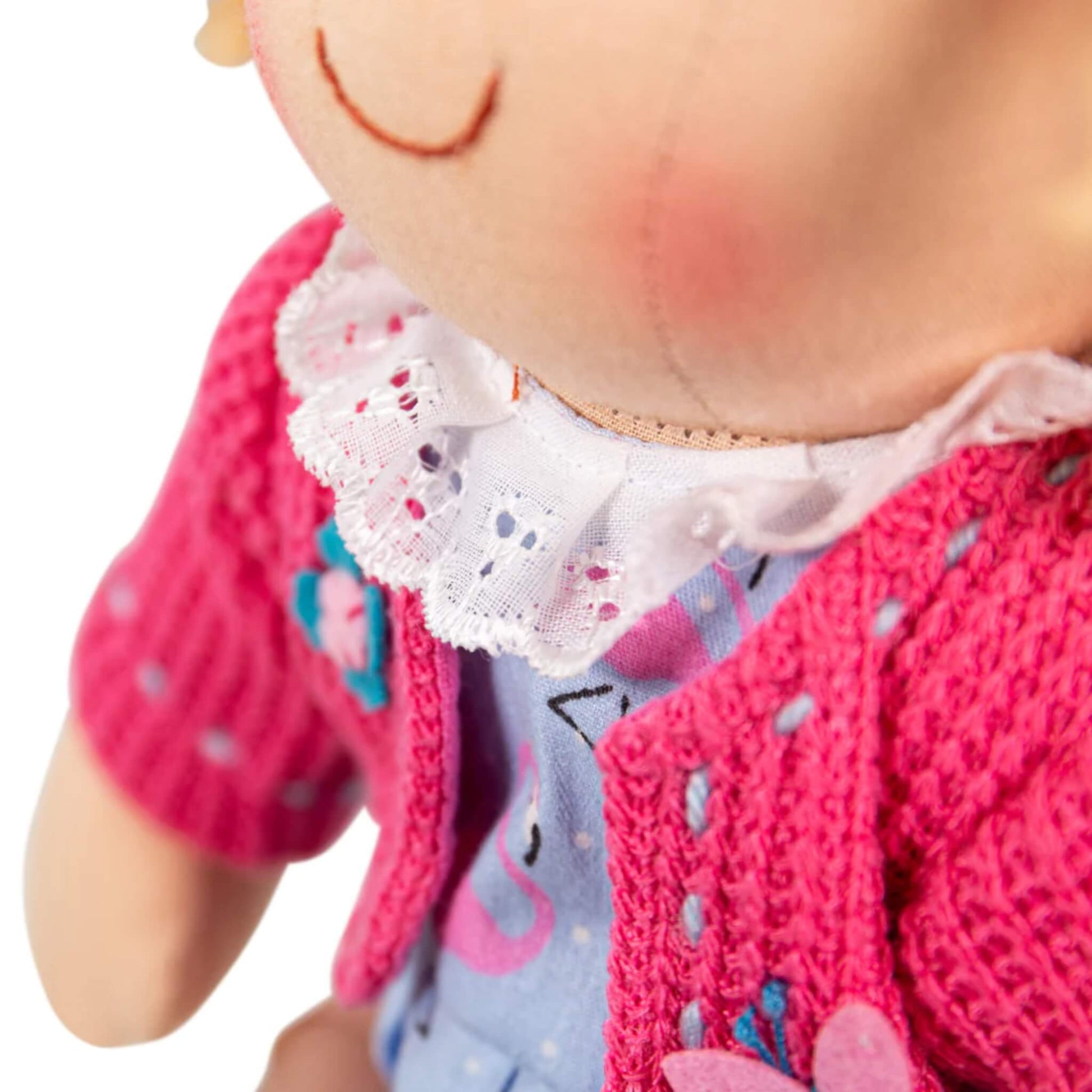 Lace-trimmed white collar detail of the doll’s dress beneath the pink cardigan, highlighting the quality stitching.