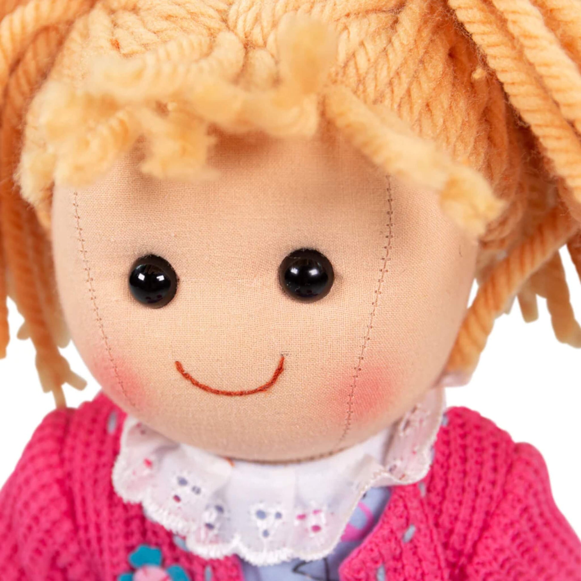 Front view of Maggie Doll’s face with wide black eyes, soft smile and tousled yarn fringe.