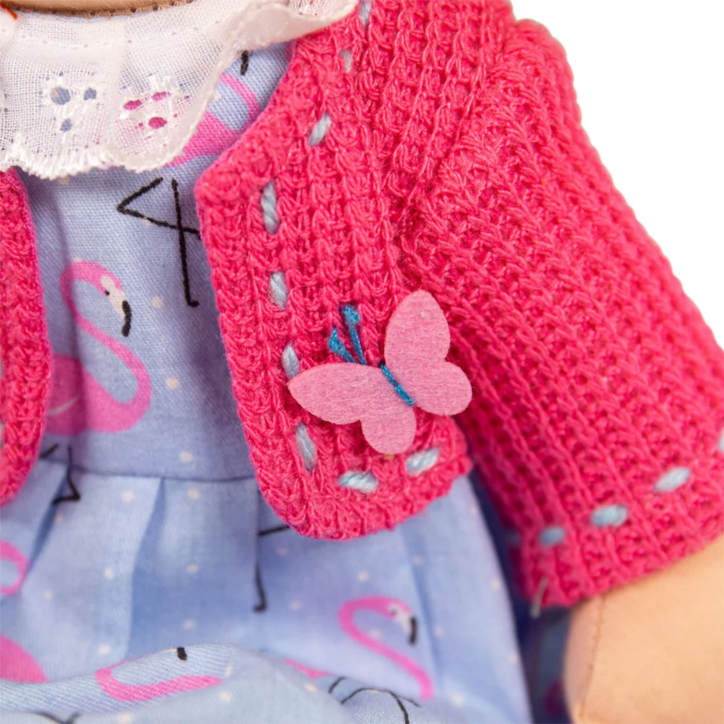 Close-up of the butterfly appliqué on Maggie’s cardigan, made of soft pink felt with embroidered details.