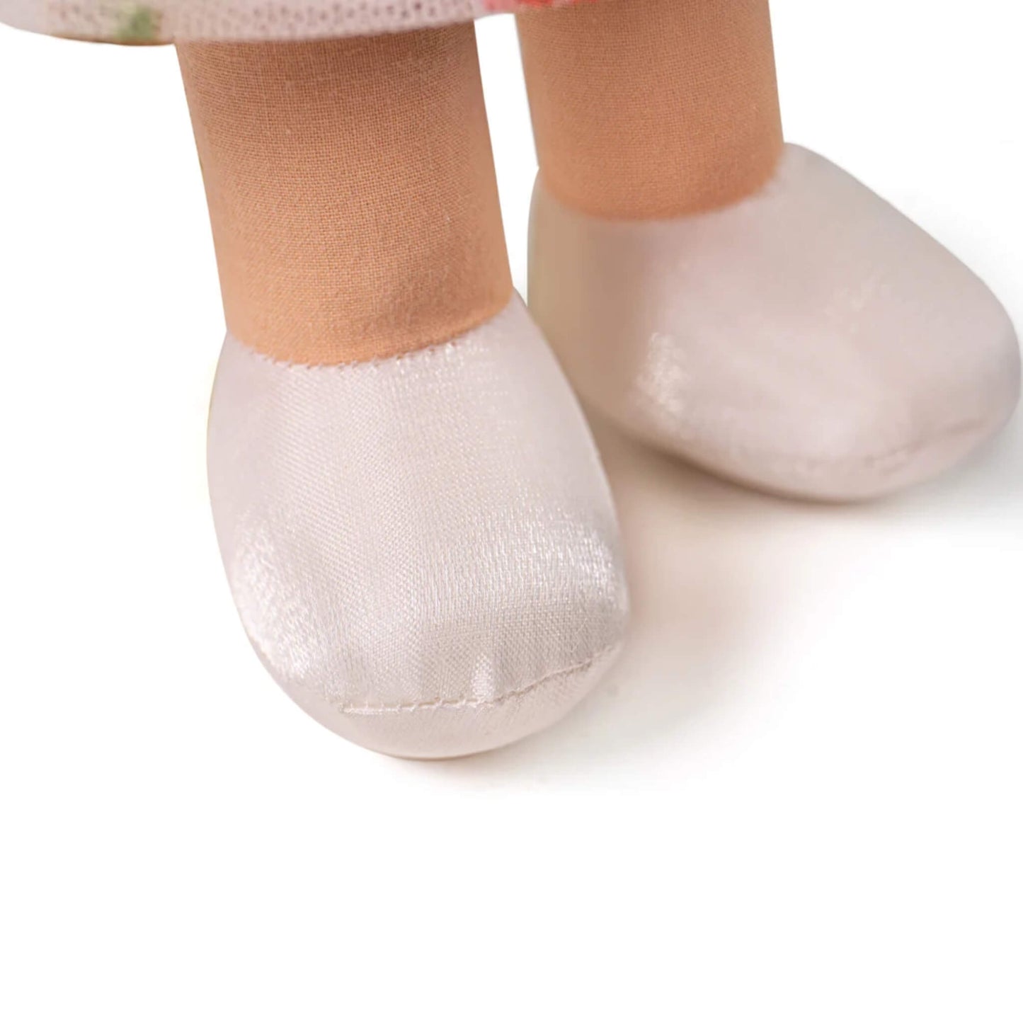 White satin-style shoes stitched onto the doll’s feet.