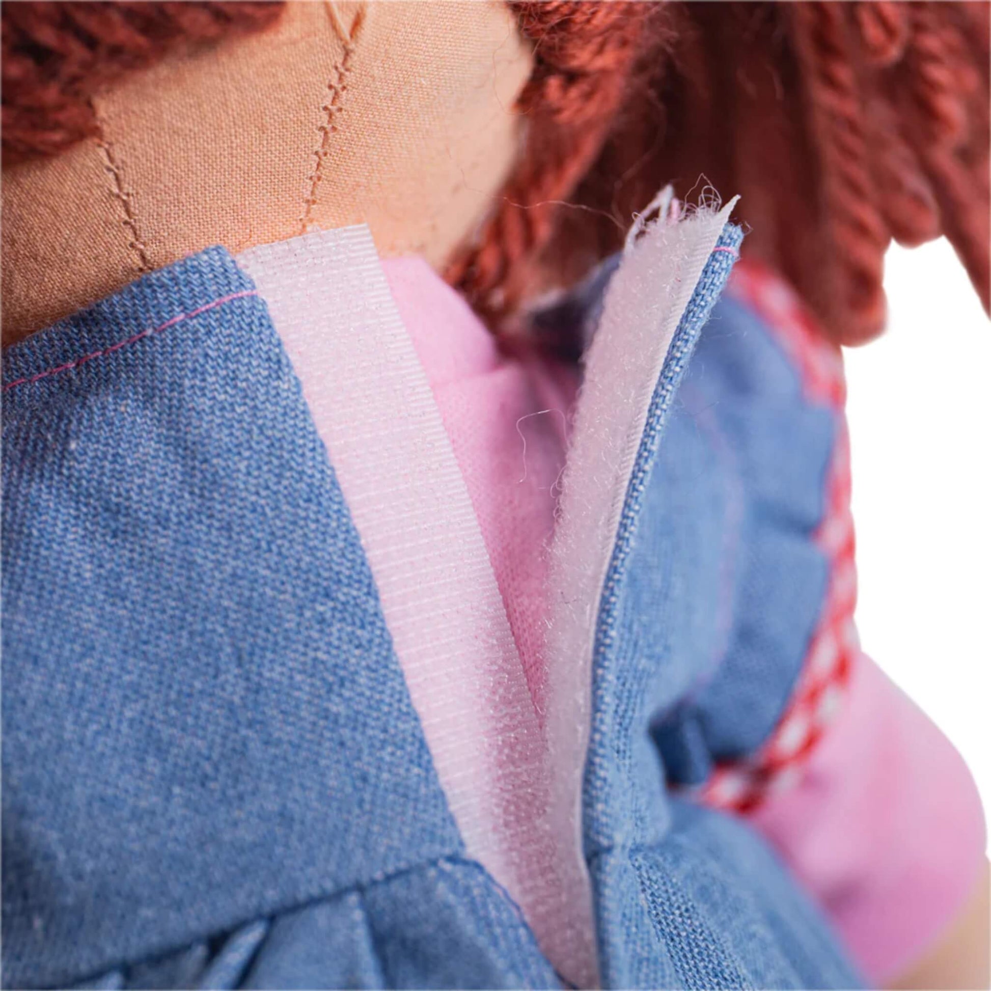 Close-up of the back of Melody Doll’s dress showing the hook-and-loop fastening, with a glimpse of her pink inner shirt and tidy stitching on the fabric.