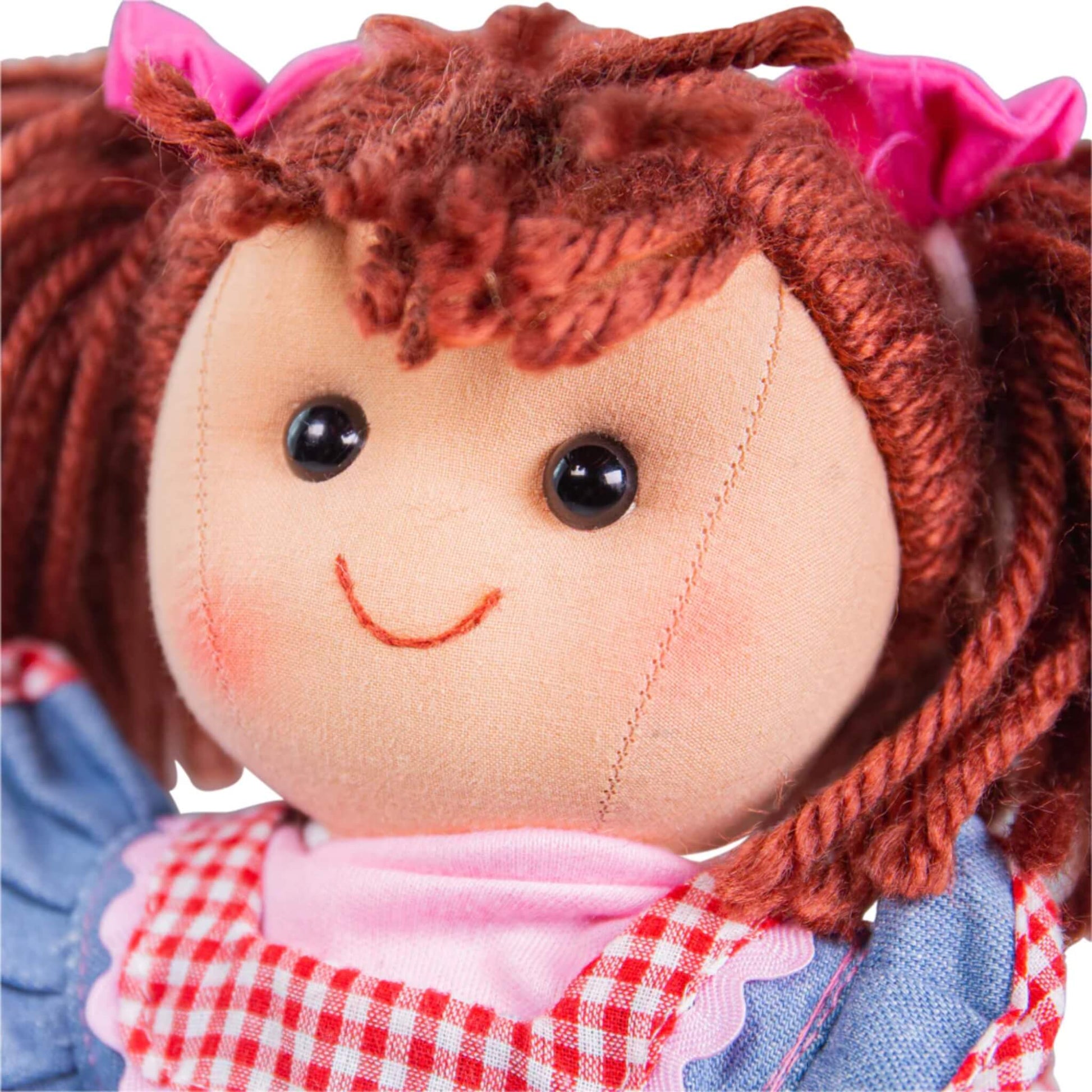 Close-up of Melody Doll’s embroidered face, showing rosy cheeks, stitched smile and shiny black eyes framed by auburn yarn hair.
