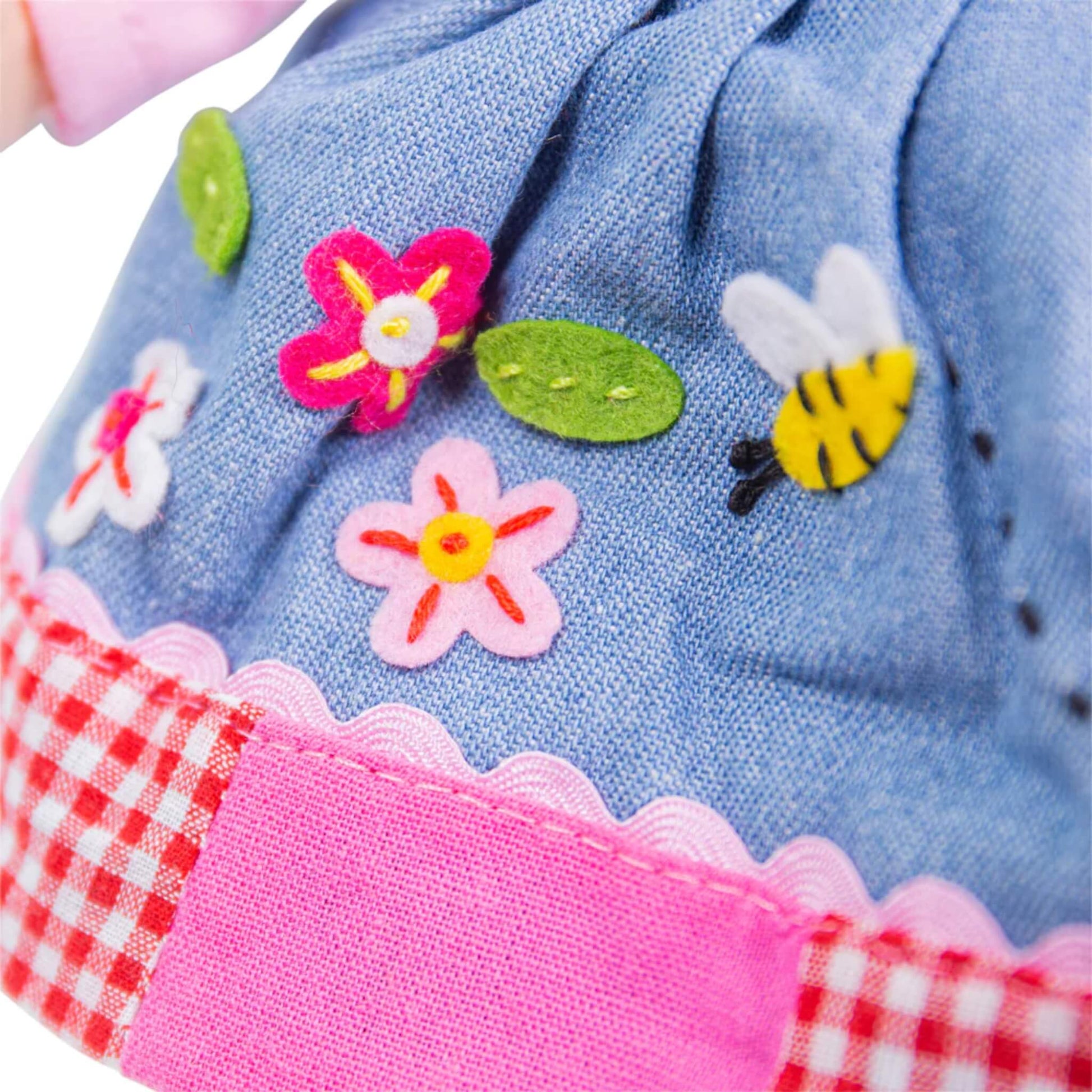 Detail of the denim-style skirt with felt flower, leaf and bee appliqués, showing a mix of soft textures and stitched accents.