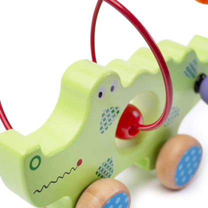Close-up of the crocodile toy showing its painted face, central cut-out, and red bead on the curved wire maze.