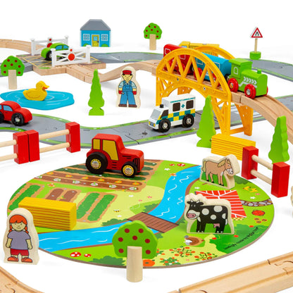 Detailed view of the farm section of the train set, showing a tractor, cow, horse, girl figure, and colourful printed farm mat with river, crops, and trees.
