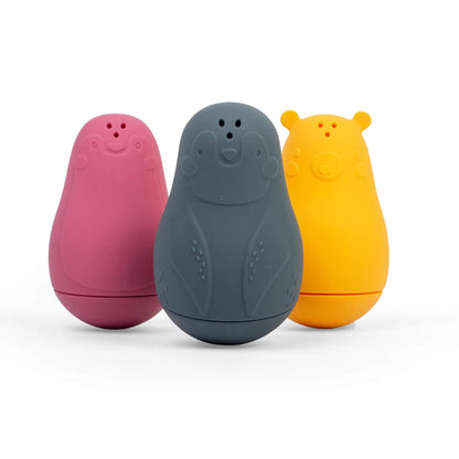 Bigjigs Toys Silicone Bath Buddies shown in a row – includes dark grey penguin, yellow polar bear, and pink seal with soft textures and water-squirting holes.