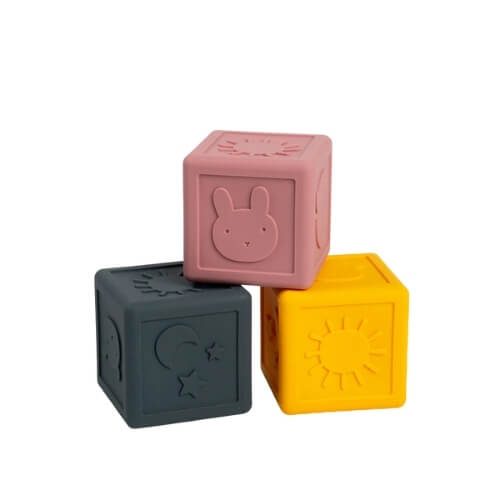 Set of three silicone sensory cubes in rose, grey, and yellow, each showing a different embossed design.