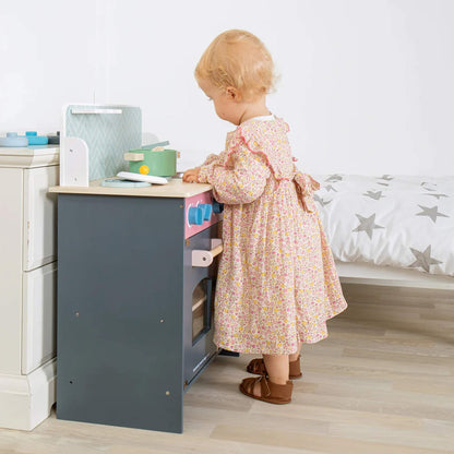 Young girl in a floral dress playing at the Simply Scandi Kitchen, exploring the worktop and hob.