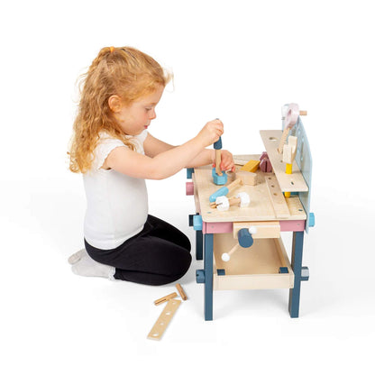 Young girl using a wooden screwdriver on the Bigjigs Tool Bench, focused on twisting a bolt into the surface.