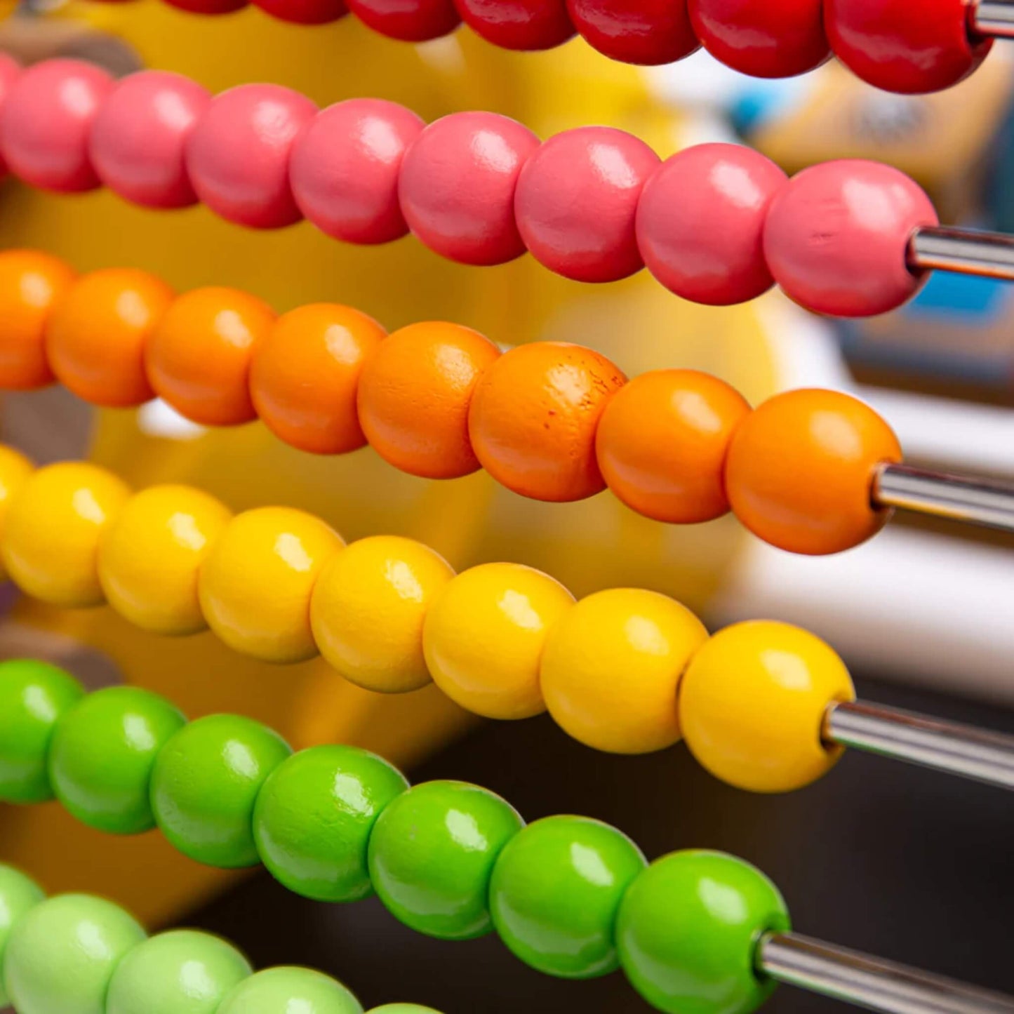Close-up of bright wooden abacus beads on metal rods.
