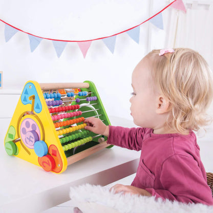 Toddler seated at a table playing with abacus side of the Bigjigs Toys Triangular Activity Centre.