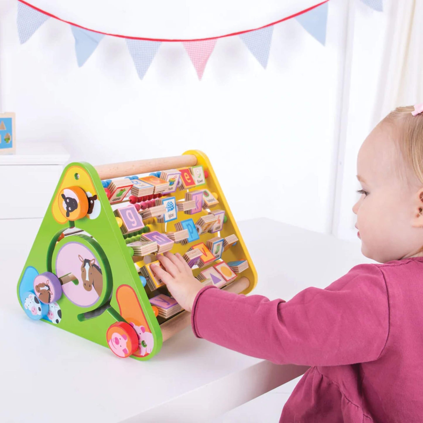 Toddler turning alphabet blocks on the Bigjigs Toys Triangular Activity Centre while seated at a table.

