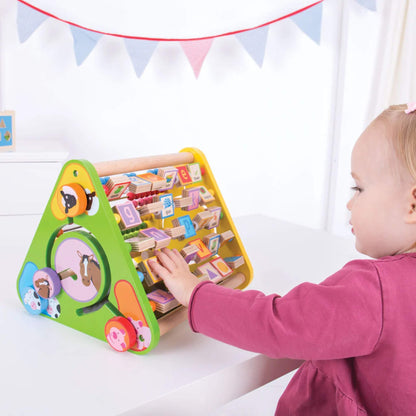 Toddler turning alphabet blocks on the Bigjigs Toys Triangular Activity Centre while seated at a table.

