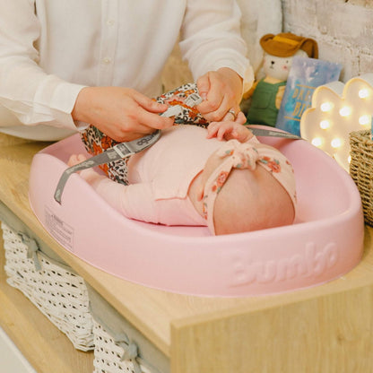Parent adjusting baby's nappy on Bumbo Cradle Pink Changing Pad.