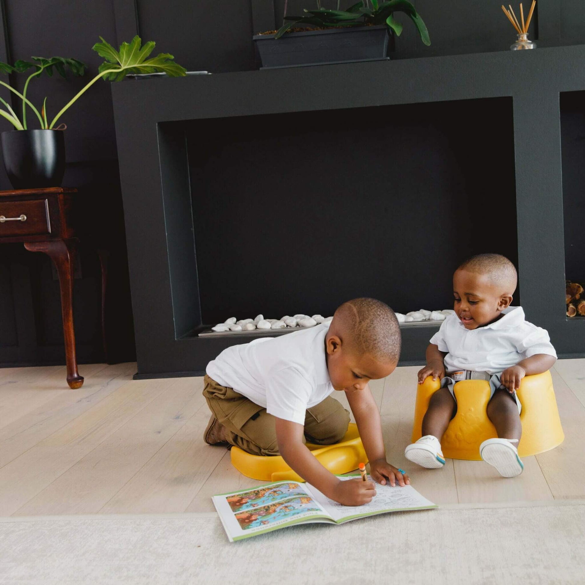 Two children using the Bumbo Elipad in Mimosa – one kneeling, one sitting, during floor play.