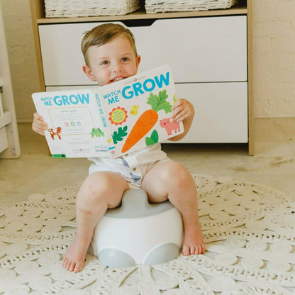 Child sitting on Bumbo Step ‘n Potty in Cool Grey while reading a book.