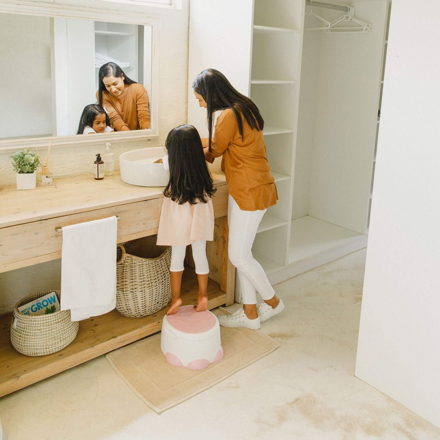 Toddler standing on Bumbo Step ‘n Potty in Cradle Pink to reach the bathroom sink.