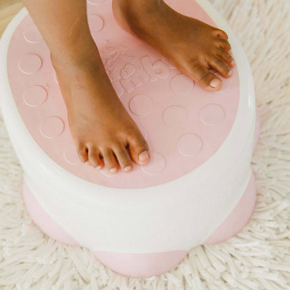 Close-up of child's feet standing safely on non-slip top of Bumbo Step ‘n Potty.