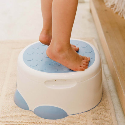 Child’s feet standing on the non-slip top of the Bumbo Step ‘n Potty in Powder Blue.