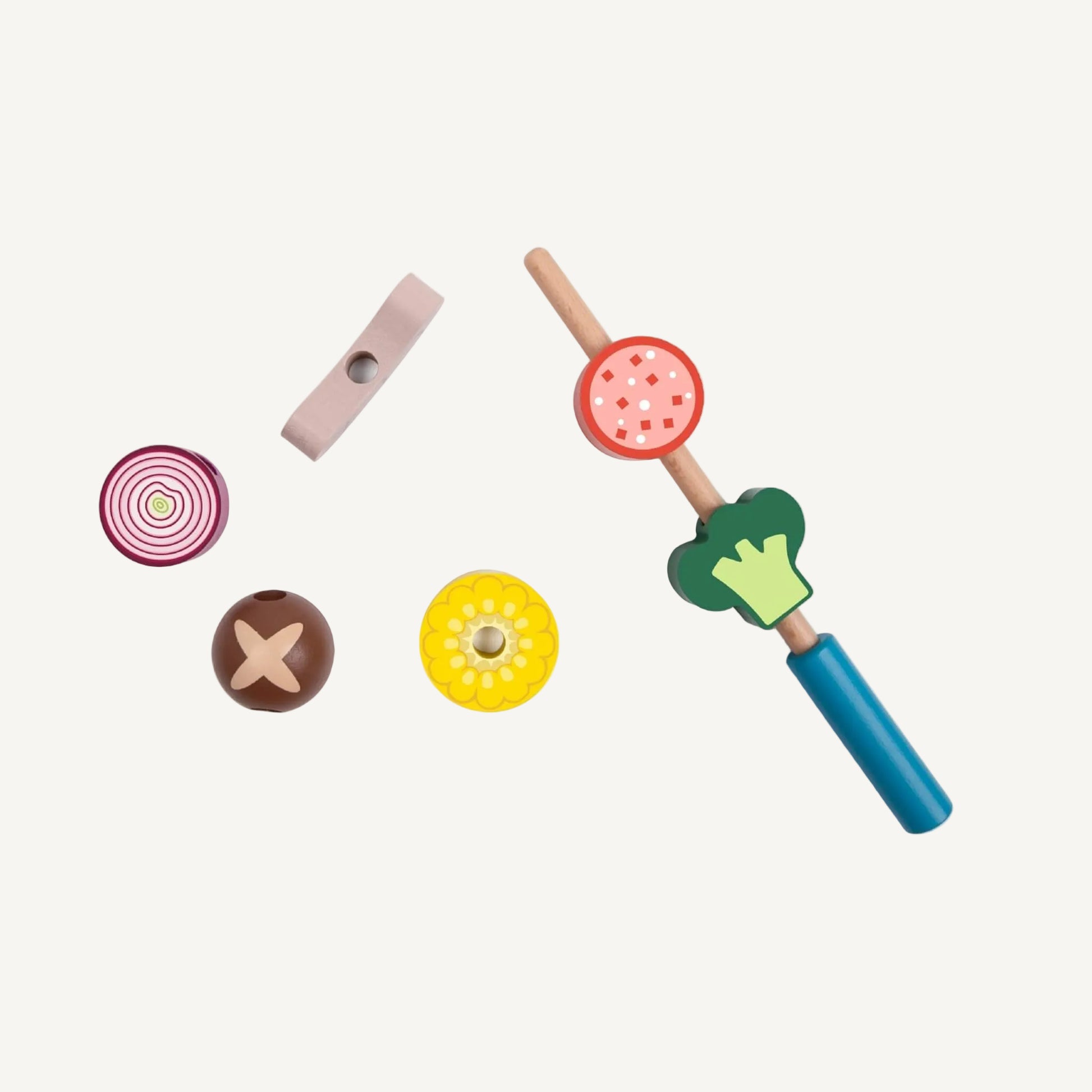 Wooden skewer toy with stackable food pieces including broccoli, sausage slice and corn threaded onto a stick.