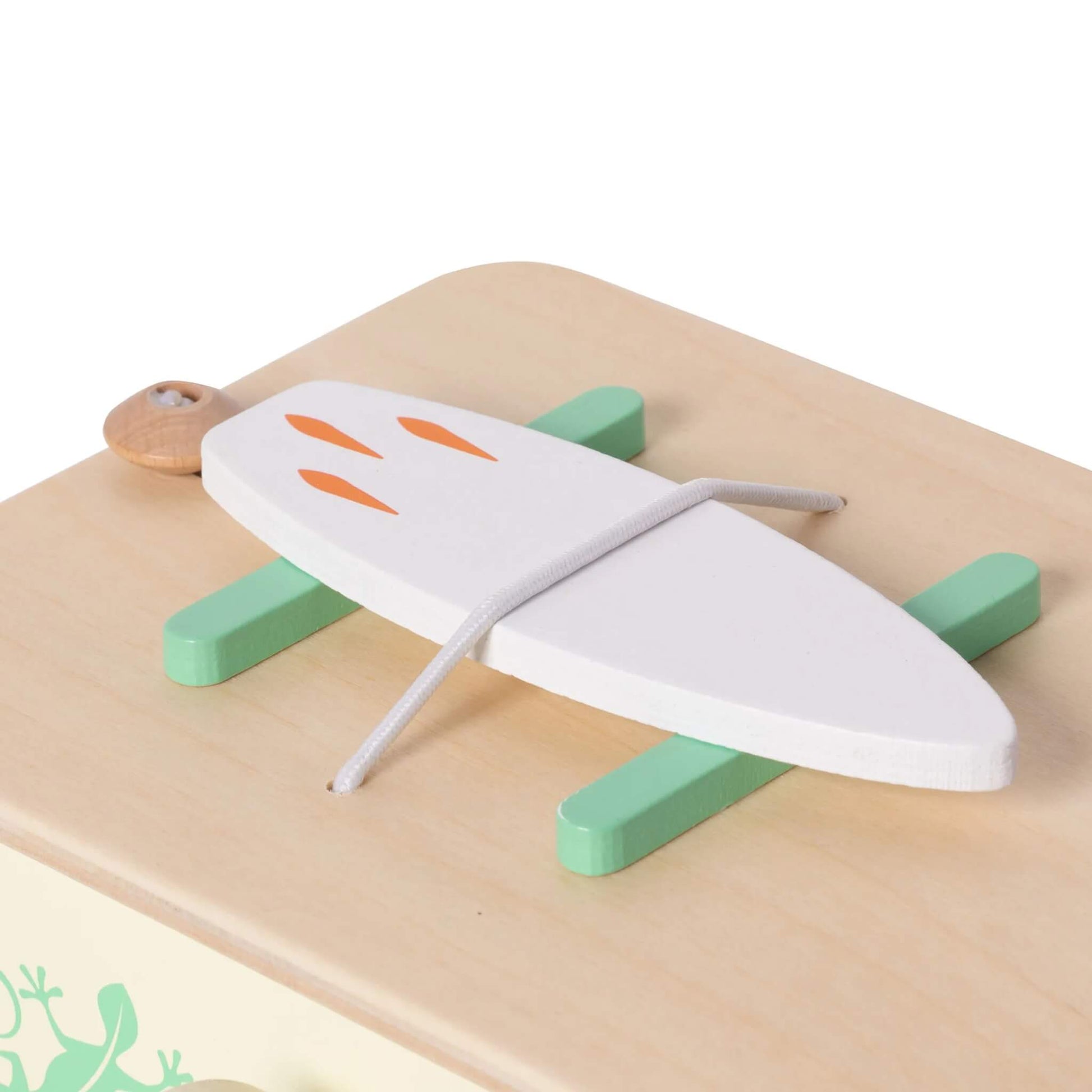 A close-up of a white wooden surfboard secured to the roof of a toy campervan with green wooden roof racks.