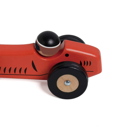 Side view of red Monaco wooden toy car, showing black wheels, black painted stripes detail.