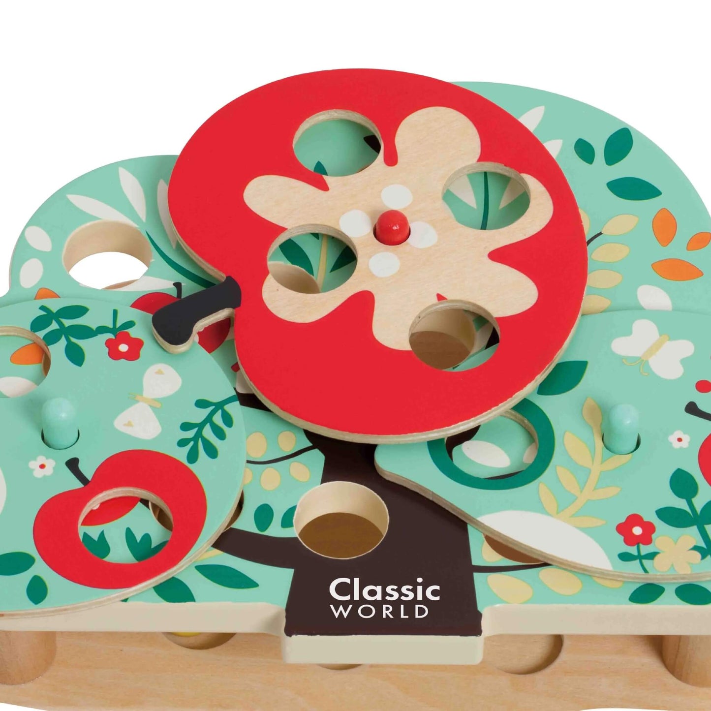 Close-up of the apple-shaped spinner on the wooden tree toy, showing painted seeds and holes to match with the wooden caterpillars.