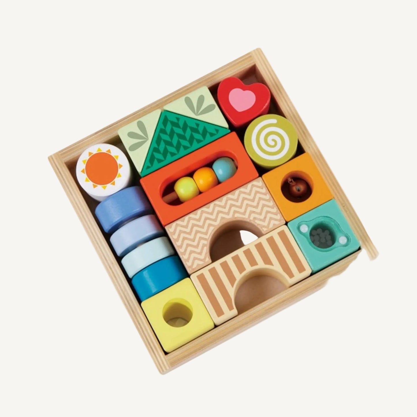 A top-down view of a square wooden tray filled with assorted sensory blocks in soft green, yellow, blue, orange, and red tones.
