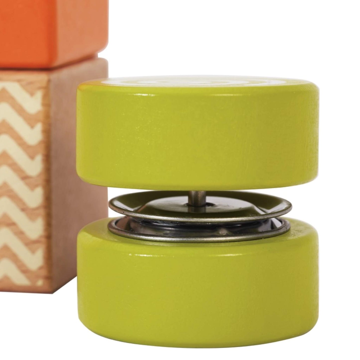 A close-up of a round wooden disc block painted green with a spiral pattern on the top surface.