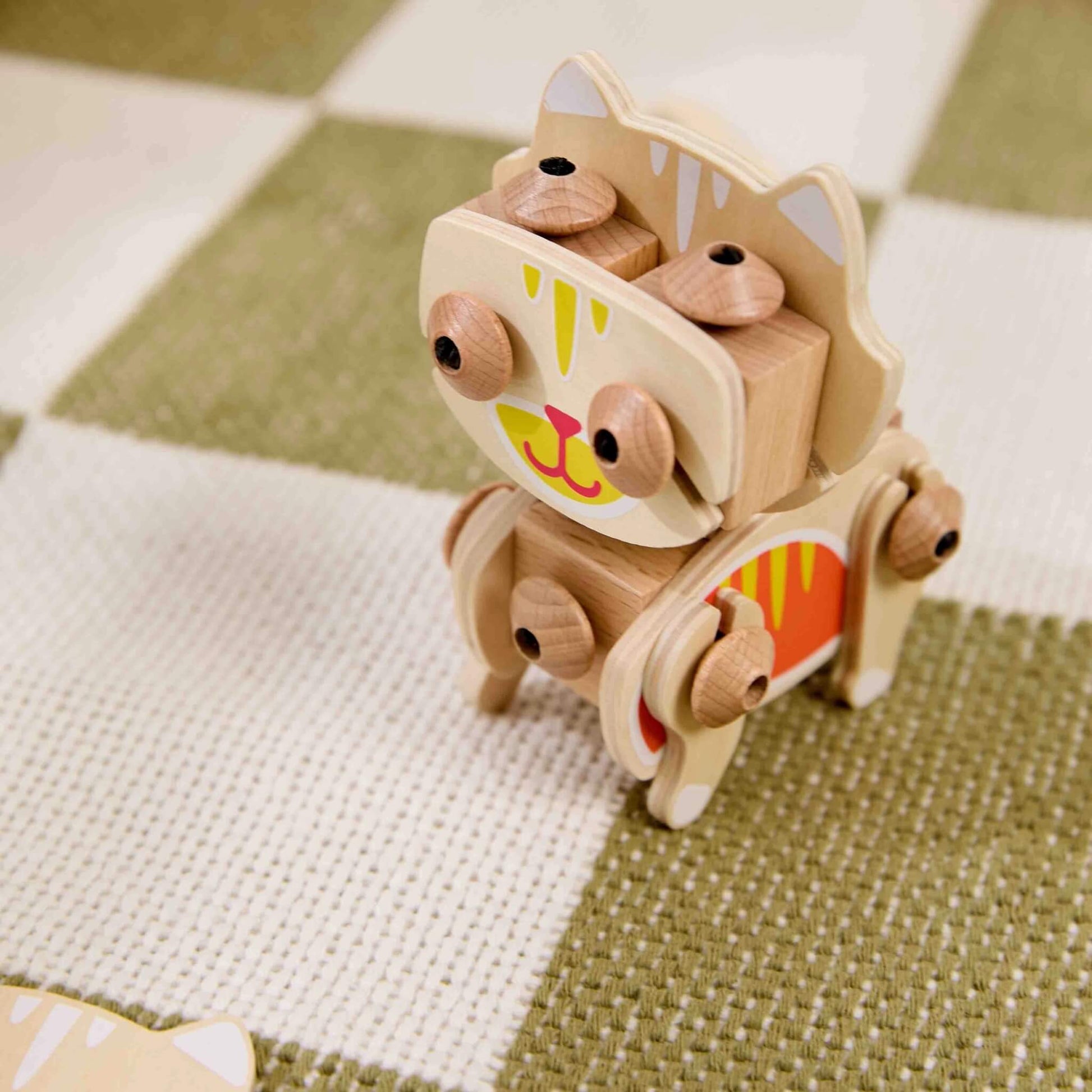 Wooden cat construction toy shown in close-up with rounded joint connectors and painted face details highlighting movable parts.