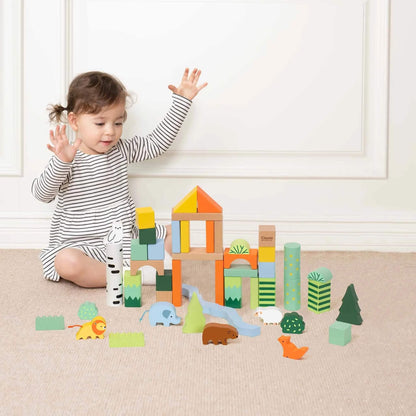 A young child in a striped dress sitting on a carpet, joyfully playing with wooden Blocks, surrounded by completed structures and animal figures.