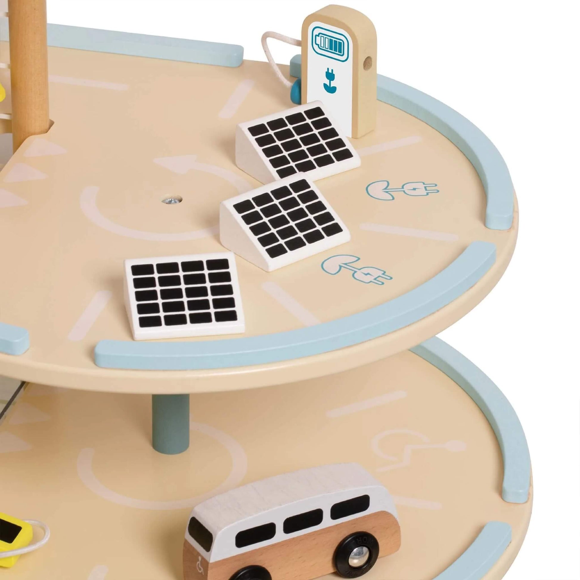 Close-up of a wooden toy garage level showing three solar panel blocks, an electric charging point, and part of a toy minivan.
