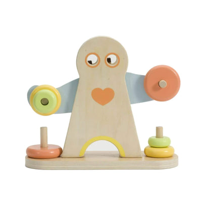 Close-up of a natural wood figure shaped like a strong man with round eyes, painted heart on the chest, and two light blue arms extending sideways, each with wooden discs in pastel yellow and orange stacked on pegs.