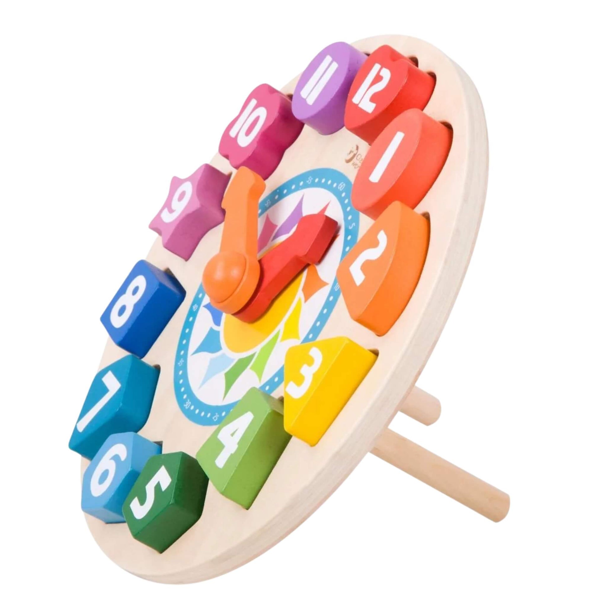 A side view of a wooden toy learning clock propped up on two pegs, showing chunky rainbow-coloured number blocks fitted into shape slots around the clock face.