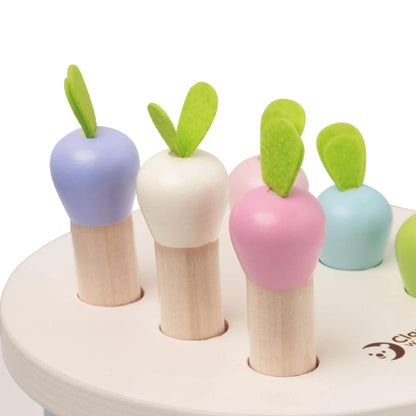 Close-up of colourful woode radish tops with green felt leaves poking out from the white circular toy top.