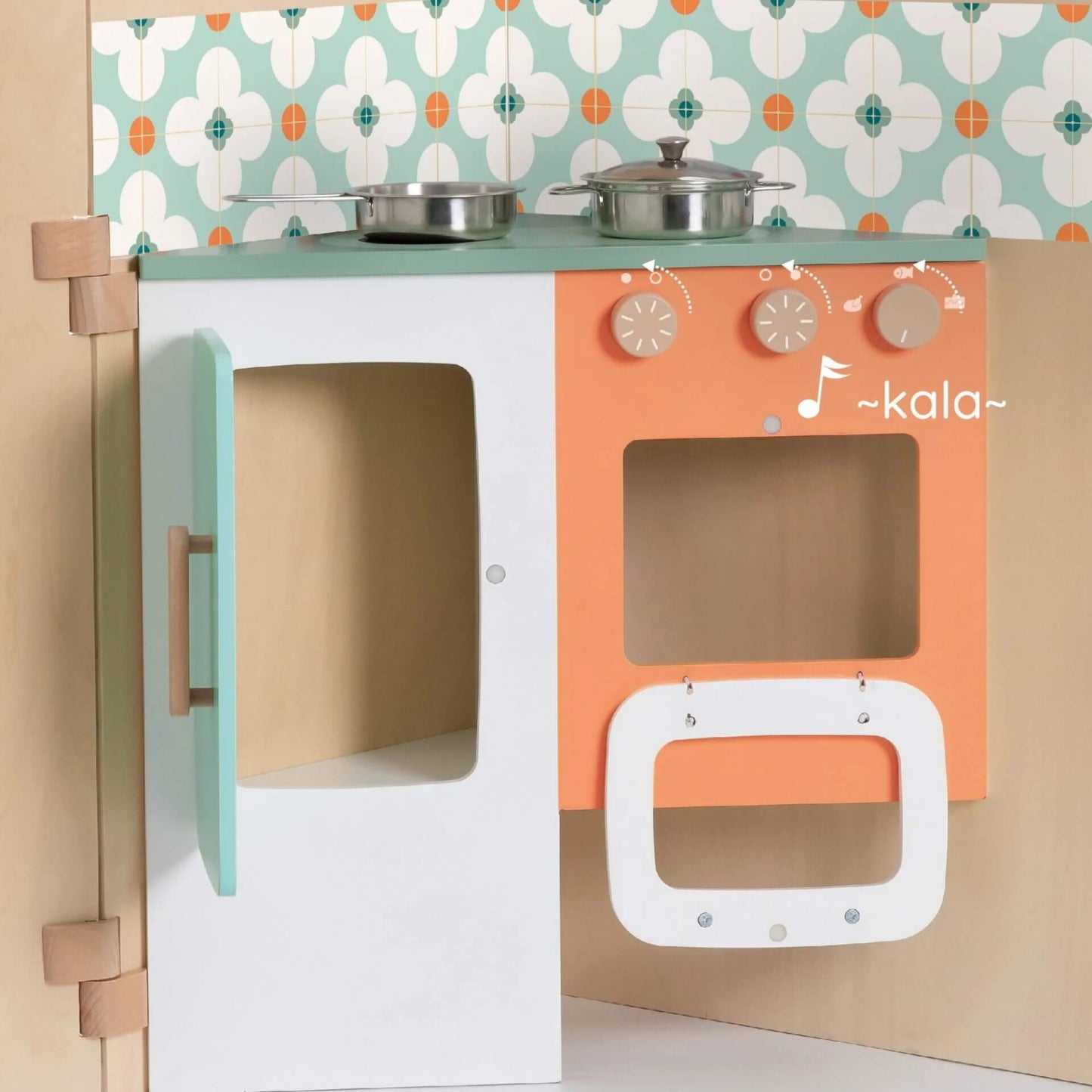 A close-up of the My Little House kitchen area featuring an orange oven, a mint green fridge, and pots on the hob.