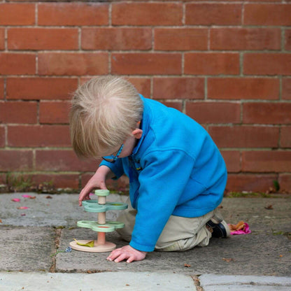 A young child investigates natural items using the Classic World Natural World Exploration set, deeply focused on the stand and lenses outdoors.