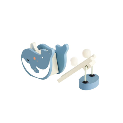 Close-up of a blue wooden whale figure and small launcher with balls, part of the ocean-themed domino play set.