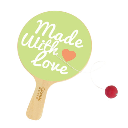 A Classic World Paddle Ball toy featuring a green paddle with the words ‘Made With Love’ in white script and an orange heart, attached to a red ball by an elastic string.