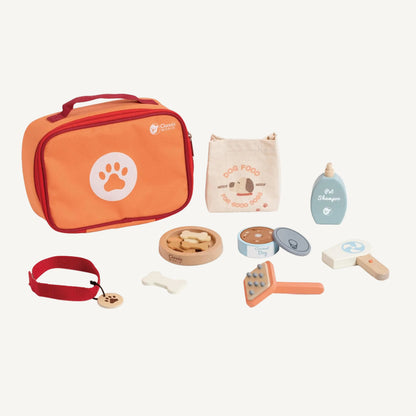 Wooden pet care toy set arranged with orange zip case, fabric dog food bag, shampoo bottle, brush, collar and wooden treats.