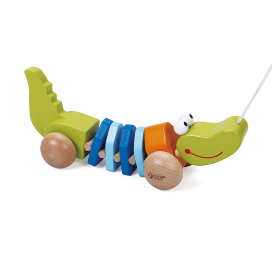 Wooden pull-along crocodile toy with green head, blue and orange midsection, and rounded wooden wheels, photographed on a white background.
